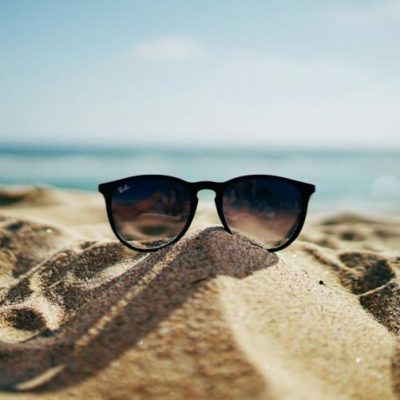 black Ray-Ban Wayfarer sunglasses on beach sand